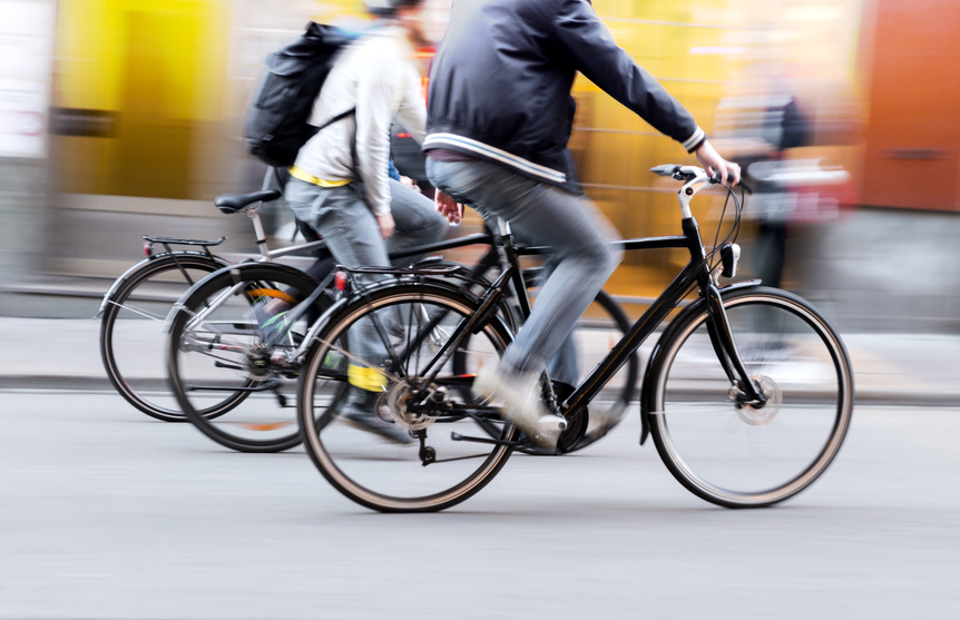 Three people are riding a bicycle on a fast pace that may cause a bicycle accident.
