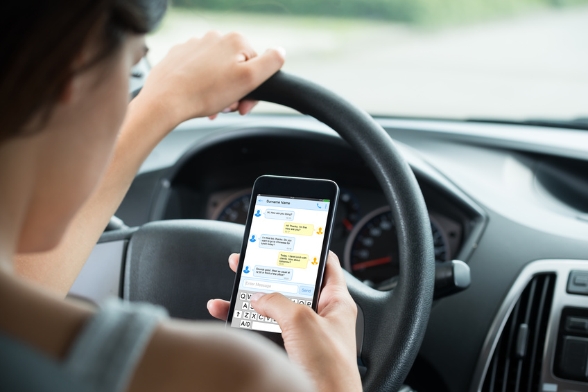 A woman is driving while texting that may lead to a car accident.