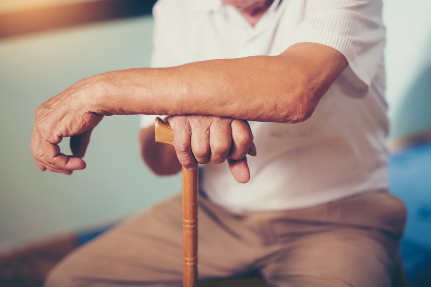 An old man sitting while holding his wooden crane and experienced nursing home abuse.