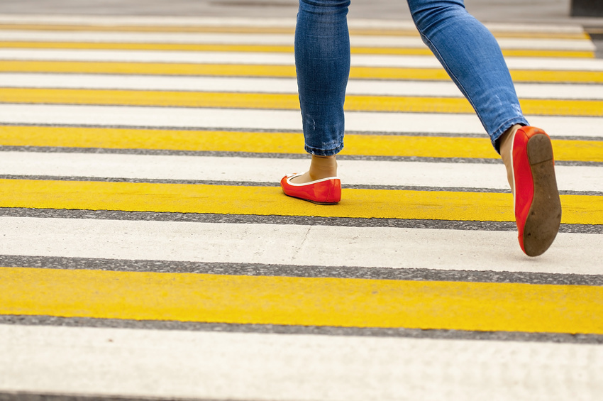 a woman crossing on a pedestrian lane with yellow and white painted on it